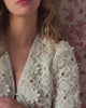 Close-up of a person wearing a white lace garment with a floral-patterned background