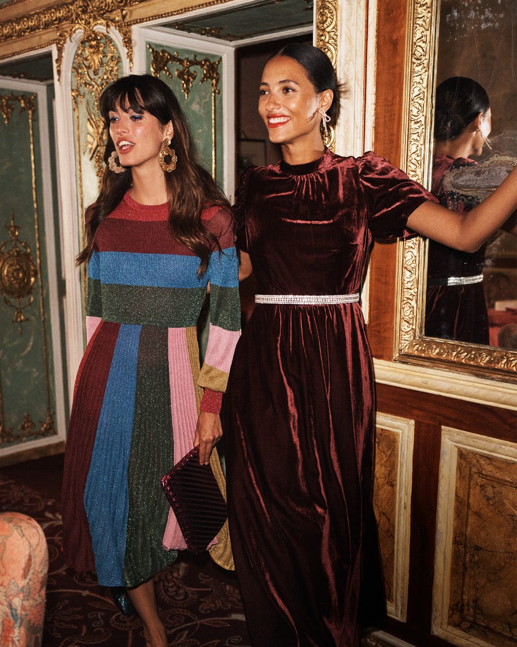 Two women dressed in Boden partywear standing in a party hall  